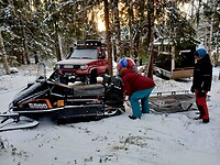 Een slee wordt bevestigd achteraan de sneeuwscooter