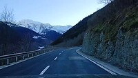 Kronkelige bergweg met sneeuw op de achtergrond