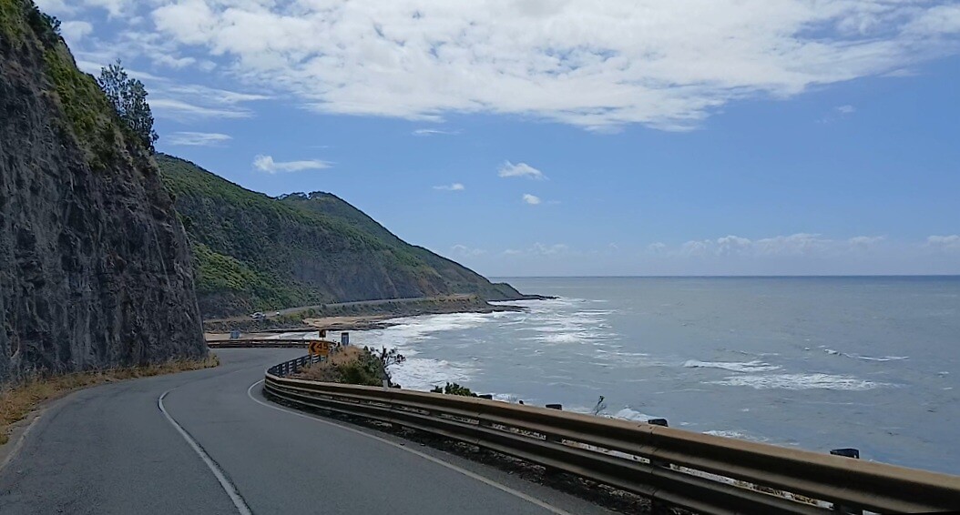 De route B100 loopt langs de kust naast de bergflanken van Otway Forest Park