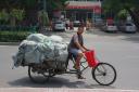 Man op fiets met troep achterop