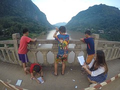 Schoolkids folding airplanes out of their notebooks and throwing them in the river!
