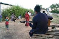 An evening in a local village: a guy singing and playing guitar while the kids are playing