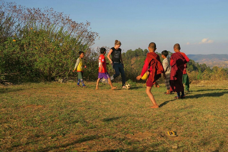 Denise is playing soccer with the local kids