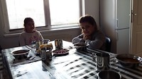 De eerste 2 zitten aan tafel, eten Speranța
