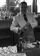 De vriendelijke bartender bereid de cocktails in  retrostyle witte jas