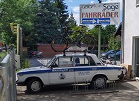 Oude Lada bij een fietsenwinkel
