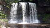 An loopt achter de waterval langs.