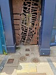 Op de grond zie je een plaquette en deze deur laat zien hoe de straatjes vroeger waren.