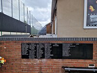 Memorial tuin. Op de achtergrond de muur en een kooi waarmee mensen hun huis beschermen tegen bommen
