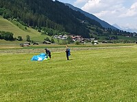 De boeren aan het werk en de paragliders genieten van hun hobby.