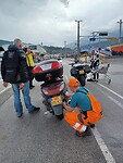 De medewerker komt vast bandjes aan de scooter bevestigen.