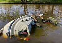 De gezonken boot met daarnaast de wielen van de heftruck net boven water.