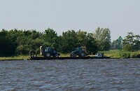 Tractoren overbrengen op een ponton om te maaien op het eiland.