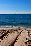 Eenzame hengel bij sleepspoor op het strand.