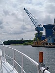 De kraanmachinist maakt de grijper even schoon in het kanaal.