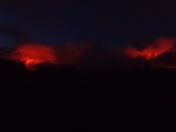 Op afstand genomen, de vulkanen bij nacht. De weerkaatsing van de lava in de gassen uit de vulkaan