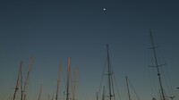 Maan terwijl de masten op de werf nog het laatste zonlicht vangen