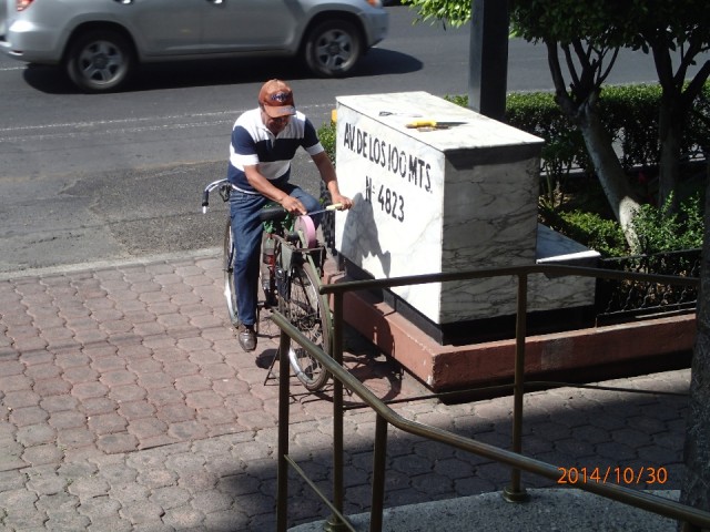 A man sharpening knifes and scissors, just sitting on a specialized bicycle!