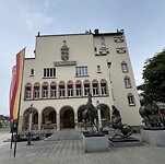 Stadhuis met een standbeeld van paarden op de voorgrond.