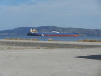 Haven Megara ,tanker wordt door sleepboot buiten de haven geloodst