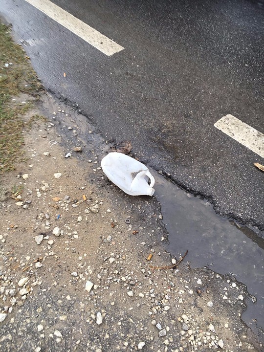 Een plastic fles langs de kapotte weg
