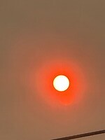 De zon op zaterdag door de rook van de branden helemaal oranje