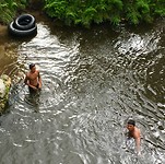 Jongens duiken geld op in de rivier bij het Maori dorp