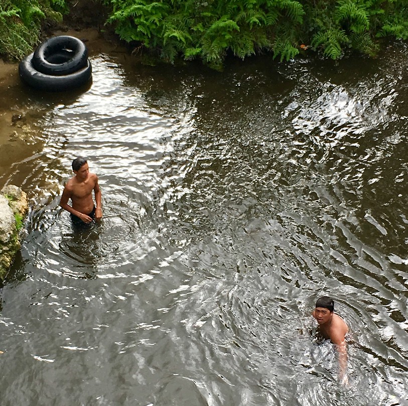 Jongens duiken geld op in de rivier bij het Maori dorp