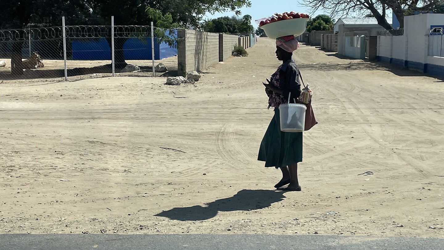 Afrikaanse vrouw met bak groente dragend op haar hoofd
