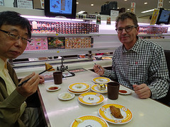 Met onze hotelier aan de sushi-trein in het sushi-restaurant. Rechts van Peter komt het bestelde