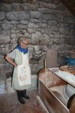 Oud vrouwtje die mais maalde tot meel