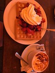 Koffiestop met koffie en wafel met vers fruit en slagroom.