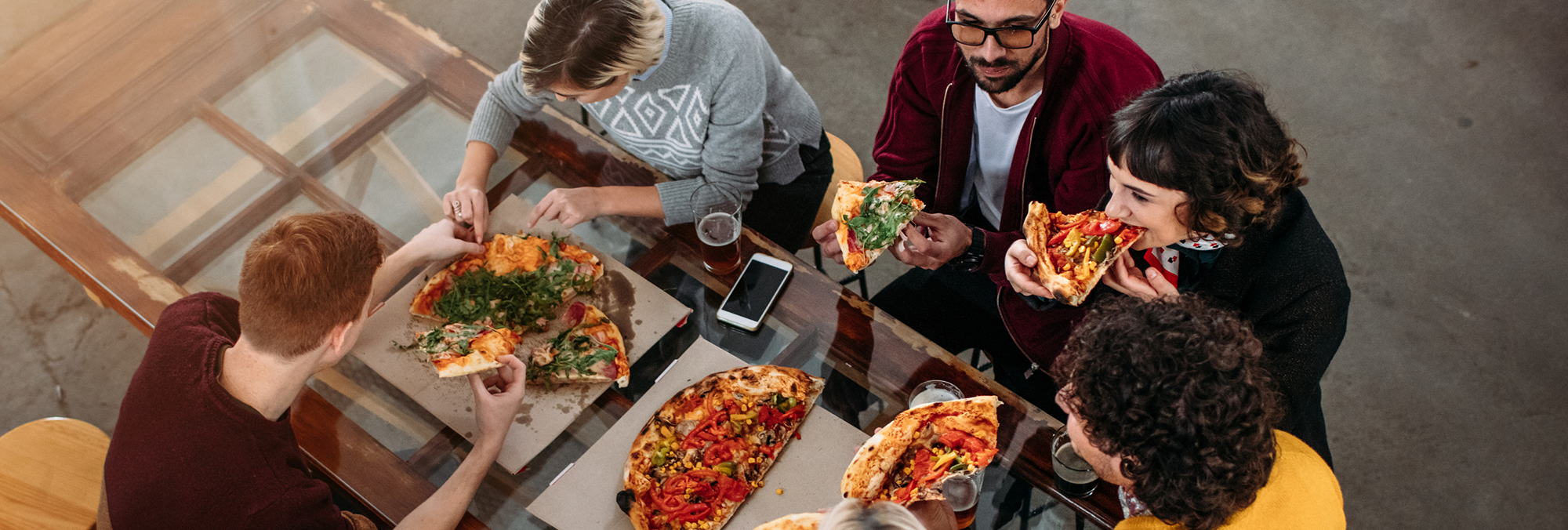 Pizza POS system customers happily enjoying pizza at the pizzeria