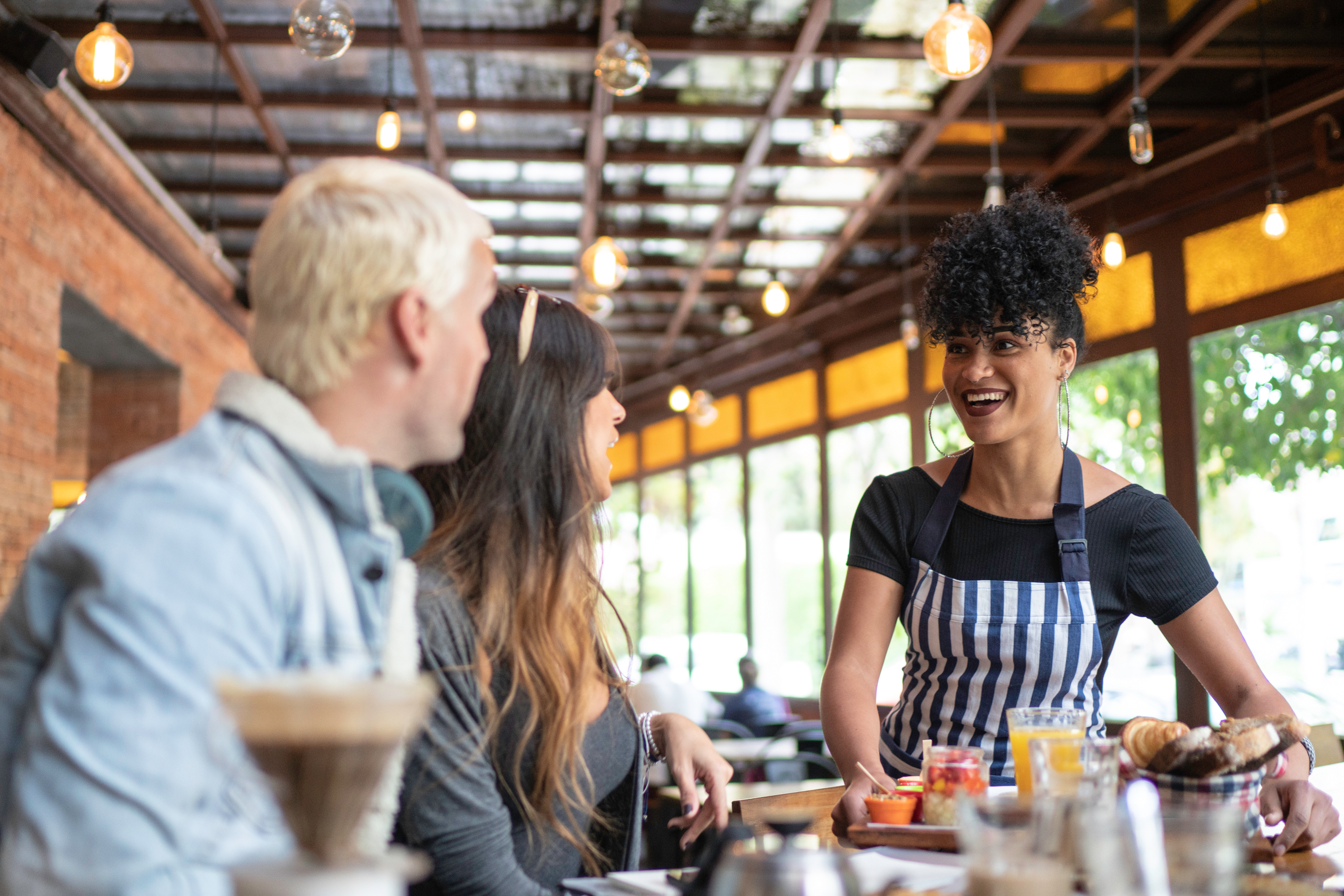 Restaurant analytics smiling employee serving a table of guests