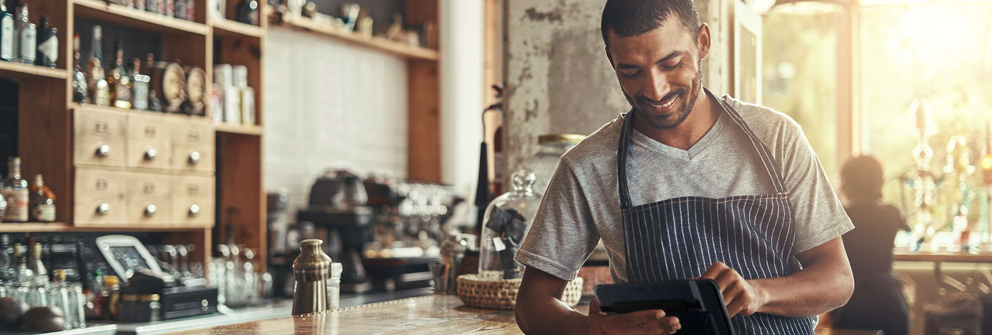 Table service POS employee standing at the bar with a tablet