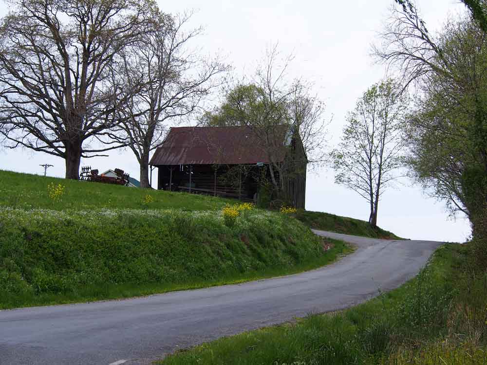 Original image of old black barn next to country road