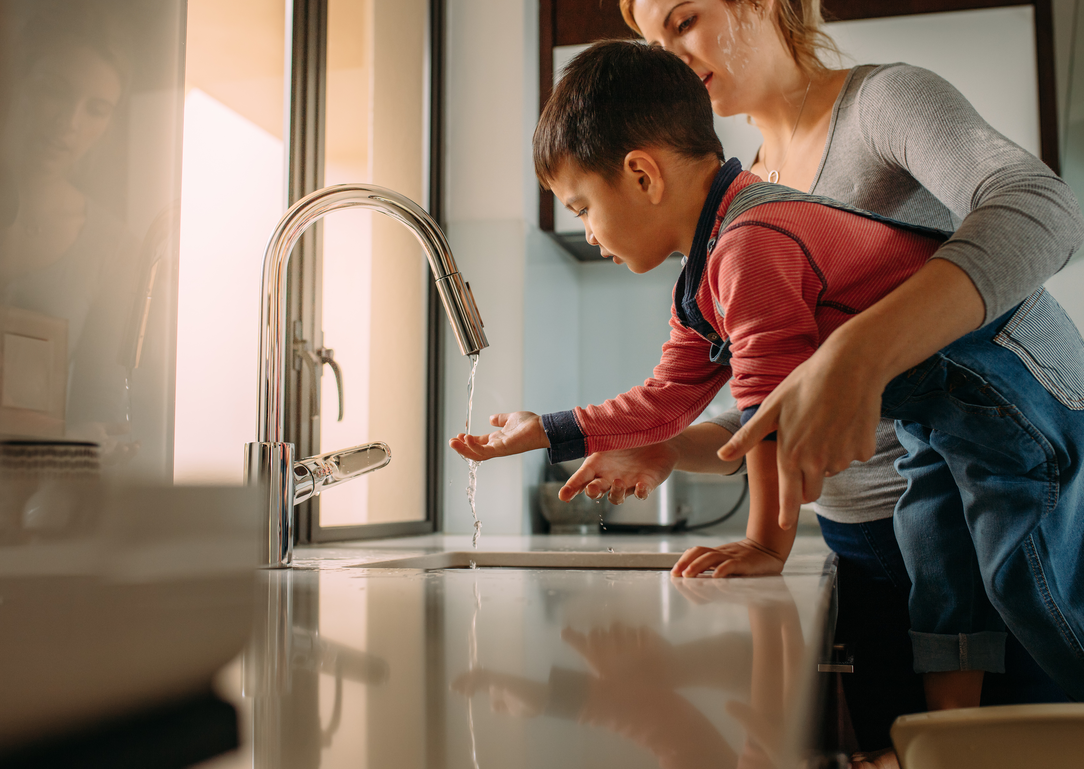 family at kitchen faucet washing hands