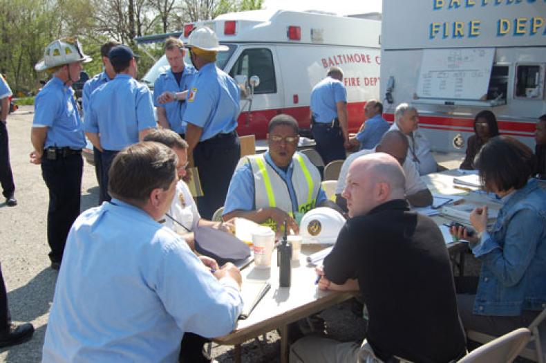 small group of people stand in a circle next to a fire truck