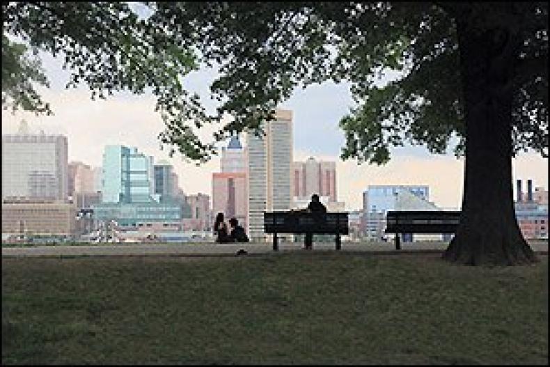 A person sitting on a park bench overlooking a city skyline