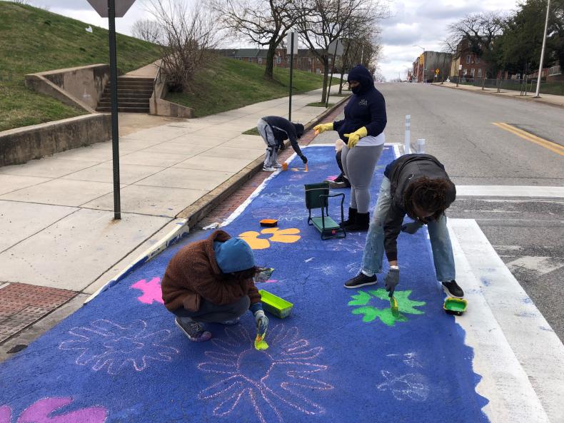 Four people painting a bike lane with colorful flowers