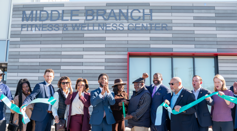 A group of adults is shown at a ribbon cutting in front of Middle Branch Fitness & Wellness Center.