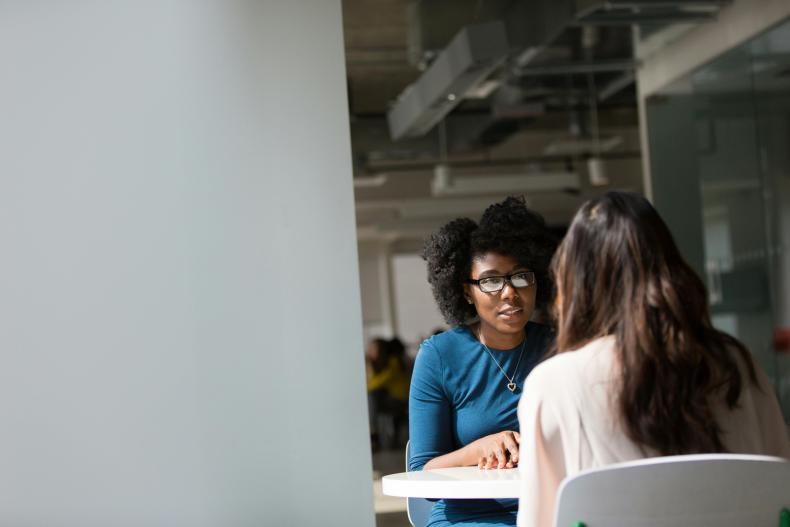 two women sitting at table talking
