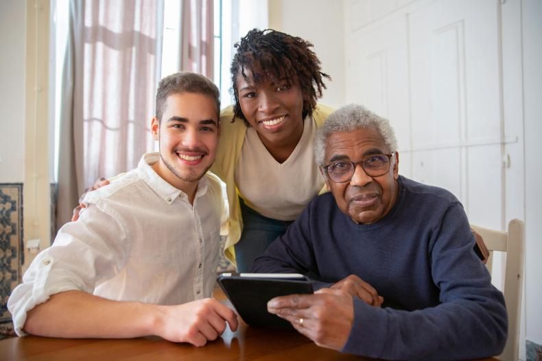 Two young adults sitting with an elderly man