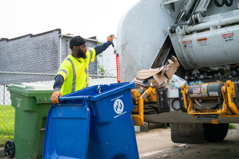 Image of Department Of Public Works Employee picking up trash during trash collection day.