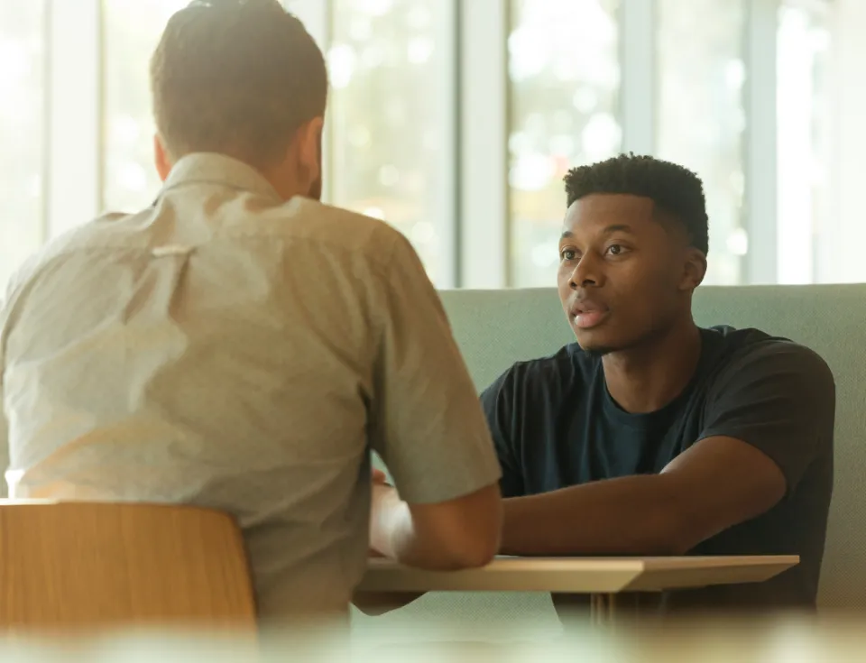 Two men talking while sitting at a table