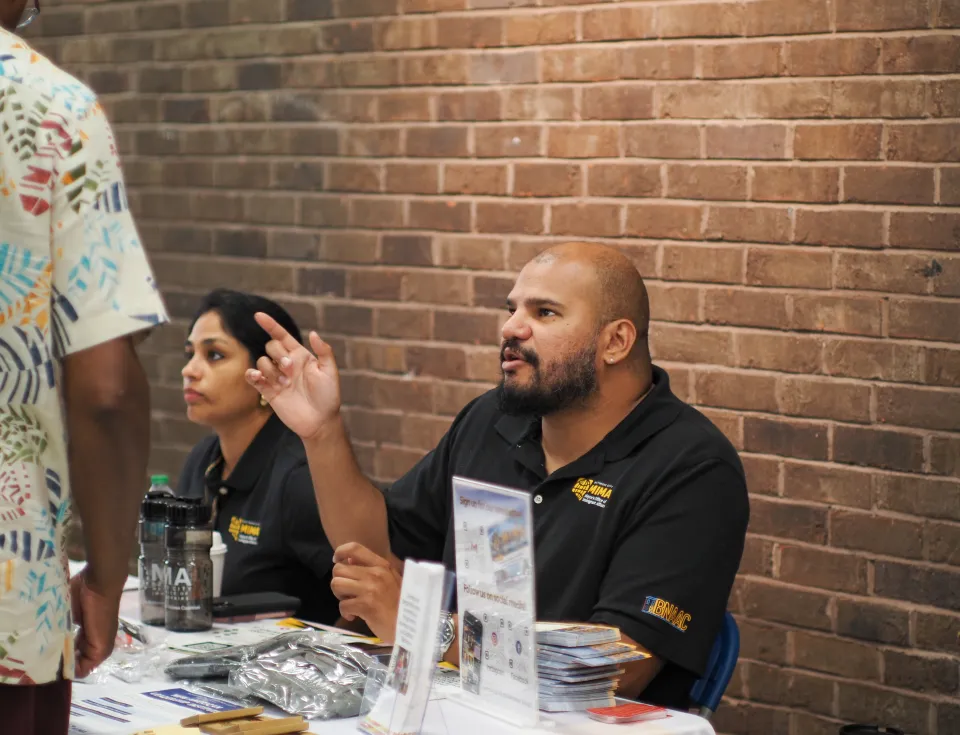 Two MIMA staff members sitting at a table and speaking with residents