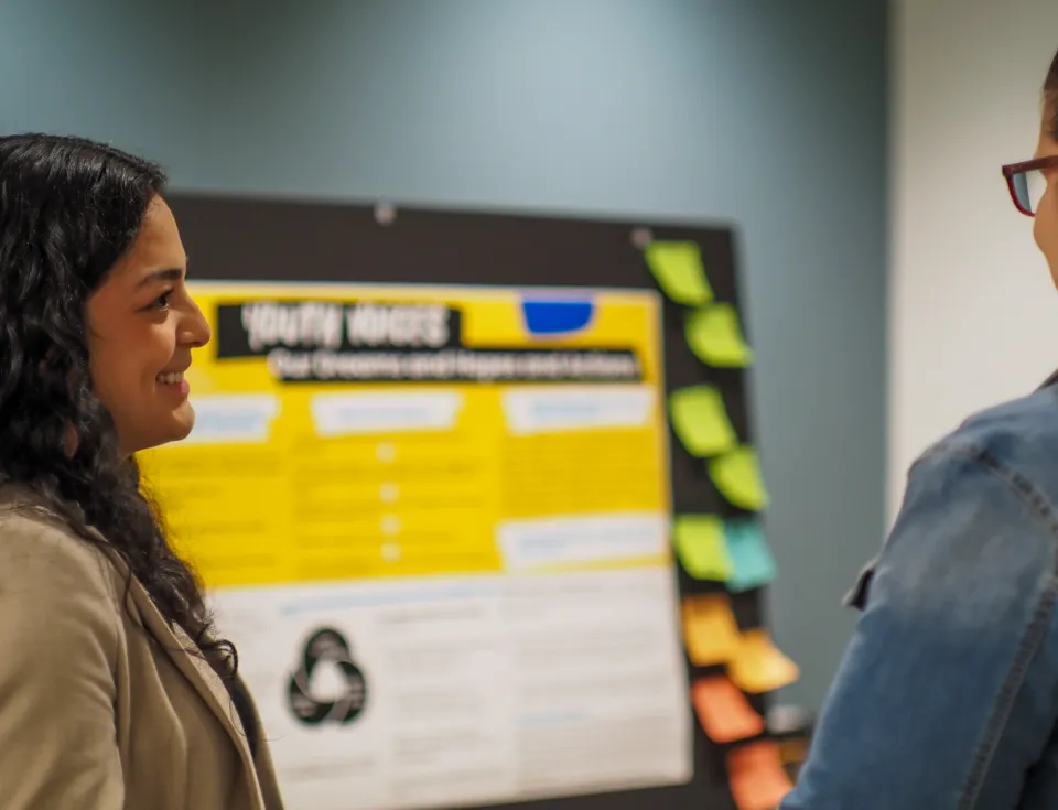 Two people having a conversation in front of a poster presentation