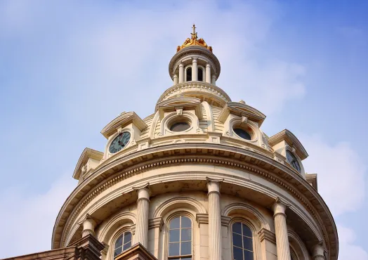 Baltimore City Hall, an ornate domed building with columns and a clock, against a clear blue sky.