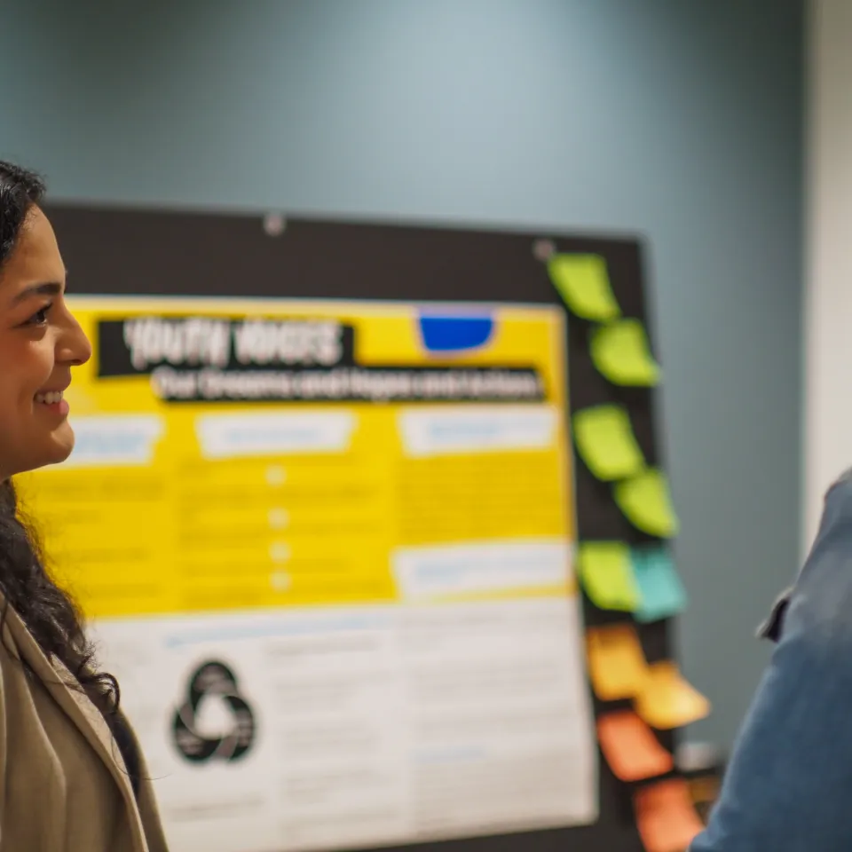 Two people having a conversation in front of a poster presentation