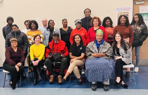 A group of people pose for a picture. Some are sitting and some are standing behind them.